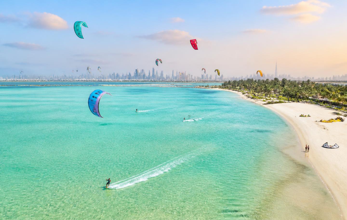 Kites flying over turquoise water at a kitesurfing spot in Dubai
